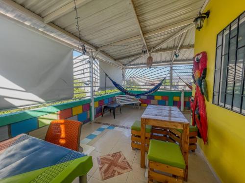 a room with a hammock and tables and chairs at Hostal Kumbaya in Santa Marta
