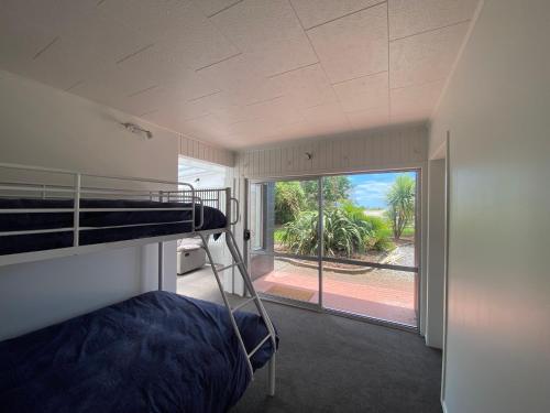a bedroom with a bunk bed and a large window at The Rock House, Patons Rock in Rangihaeata