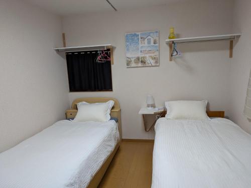 two beds in a room with white sheets at marusan houseマルさんの家 in Osaka