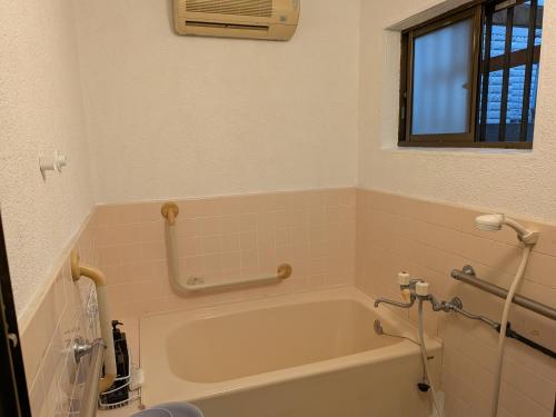 a bathroom with a bath tub and a window at marusan houseマルさんの家 in Osaka