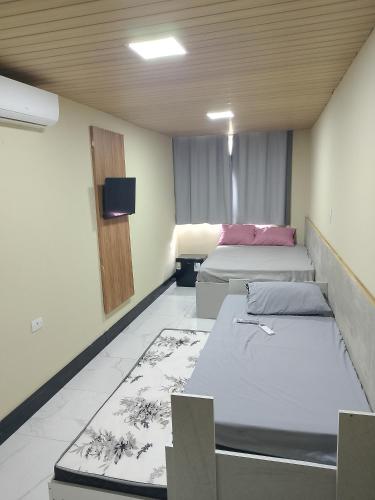a room with two beds and a tv on the wall at EL Shaday in Guarujá
