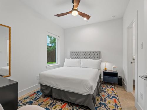 a white bedroom with a bed and a ceiling fan at Modern Dallas Townhome with Private Rooftop, City View, Private Parking & Grill in Dallas