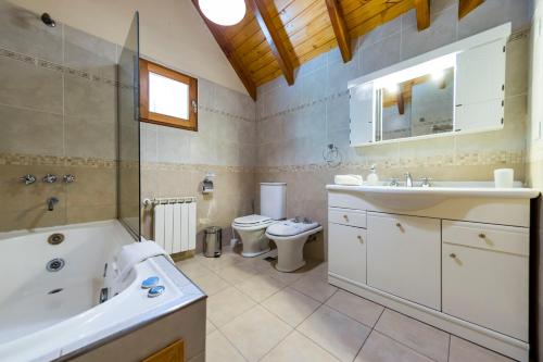 a bathroom with a tub and a sink and a toilet at Bosque Dormido Cabañas & Spa in San Carlos de Bariloche