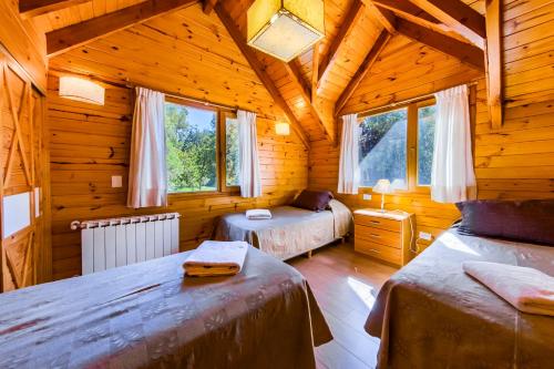 a bedroom with two beds in a wooden cabin at Bosque Dormido Cabañas & Spa in San Carlos de Bariloche