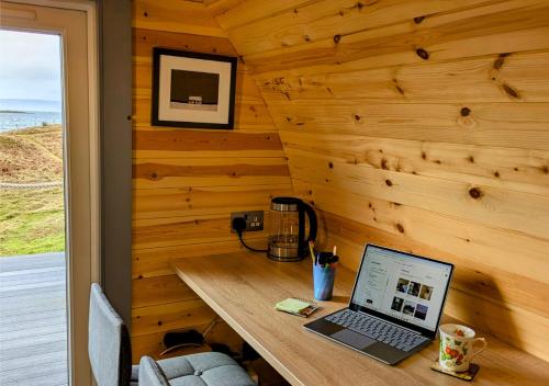 a laptop computer sitting on a wooden desk in a room at Herons Rest Pod By The Sea in Morar Station