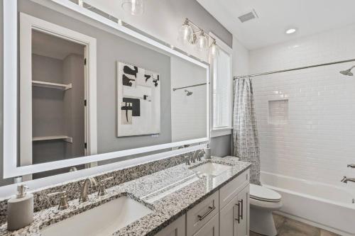 a white bathroom with two sinks and a toilet at Gated Parking + Fire Pit | Near Zoo + Rhodes in Memphis