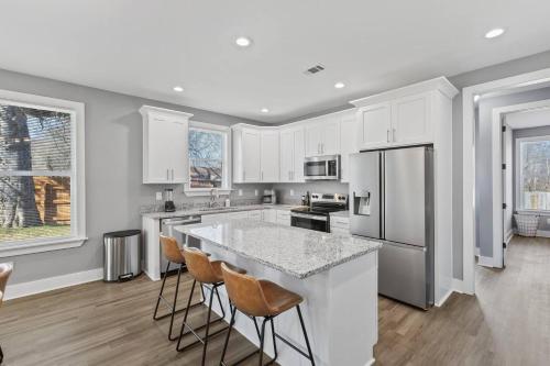 a kitchen with white cabinets and a large island with bar stools at Gated Parking + Fire Pit | Near Zoo + Rhodes in Memphis