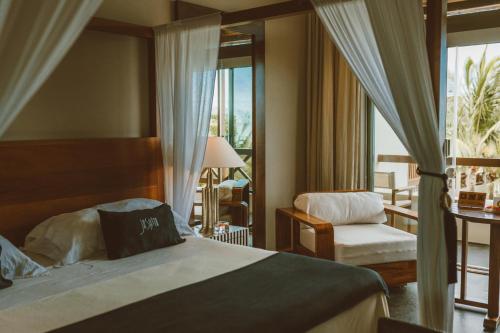 a bedroom with a bed and a chair and a window at Coral Breeze Retreat in Balcheil