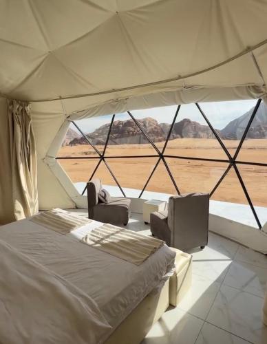 a bedroom with a bed and two chairs in a tent at Star Gate Camp in Wadi Rum