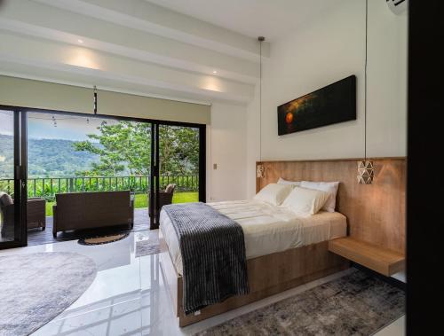 a bedroom with a bed and a large window at La Danta Lodge - Rio Celeste in Bijagua