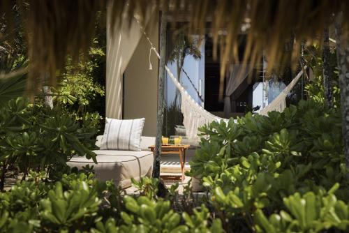 a porch with a hammock and a chair and some plants at Beachfront Bliss Suite in Balcheil