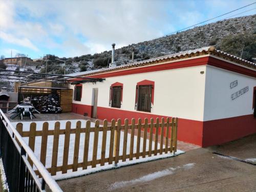 a small white and red building with a fence at El Almendro de Fuentes Nuevas in Castril