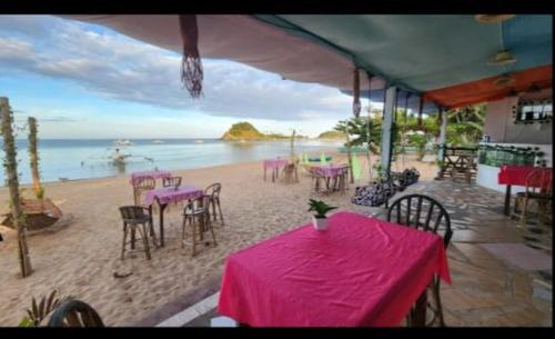 a table with pink tables and chairs on the beach at Dandal Bay view in El Nido