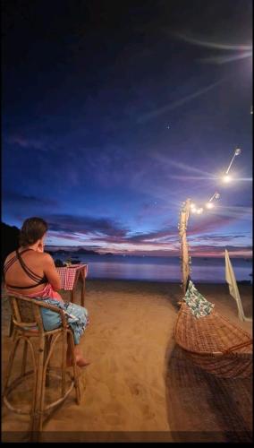 a man sitting in a chair on the beach at Dandal Bay view in El Nido
