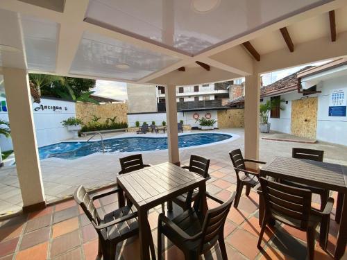 a patio with tables and chairs and a swimming pool at Hotel Casa Antigua Buga in Buga