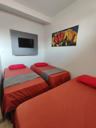 a room with three beds and a tv on the wall at Quarto Triplo Comercial - Queen's Hotel in Formosa