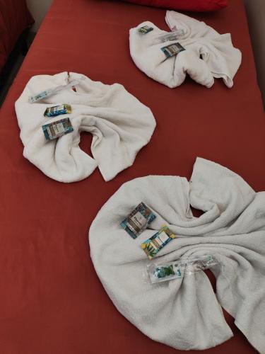 a group of white towels on a bed at Quarto Triplo Comercial - Queen's Hotel in Formosa