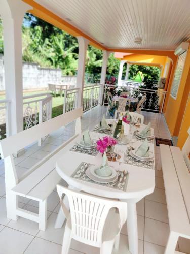 a white dining table and chairs on a porch at Exceptional villa KODEÏA - private spa & panoramic view in Sainte-Marie