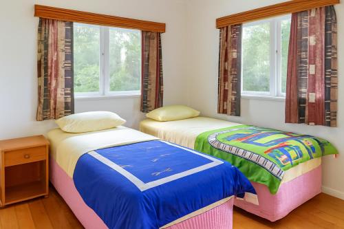 two beds in a room with two windows at Boxed Bliss on Fox in Hamilton