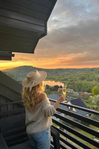 a woman holding a glass of wine on a balcony at Amaretto Apartamenty Solina centrum in Solina
