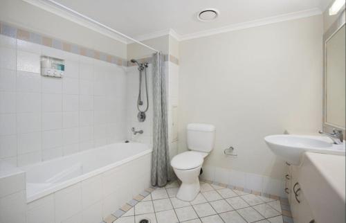 a white bathroom with a toilet and a sink at Discounted Palm View Studio with Pool And Spa in Gold Coast