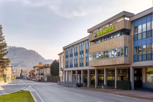 a building on a street with a mountain in the background at B&B HOTEL Como Baradello in Como