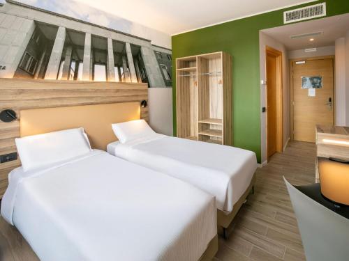 two beds in a room with green walls at B&B HOTEL Latina in Latina