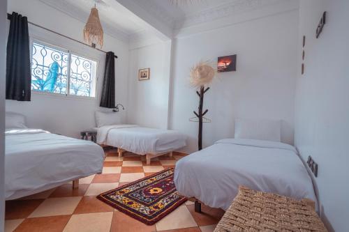 a white room with two beds and a window at Olas Surf Camp in Imsouane