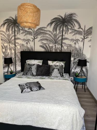 a bedroom with a white bed with palm trees on the wall at L'Immortelle in Zonza