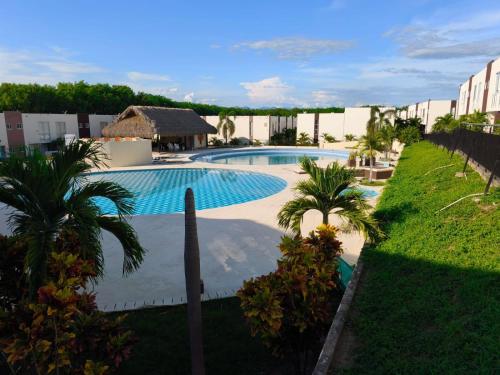 a swimming pool in a resort with palm trees at Casa de Verano Málaga Confort Sol y Piscina in Ricaurte