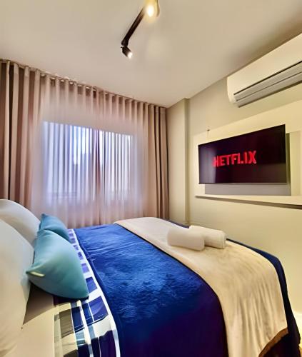 a bedroom with a bed with a tv on the wall at Studio Prime, no centro de CWB in Curitiba