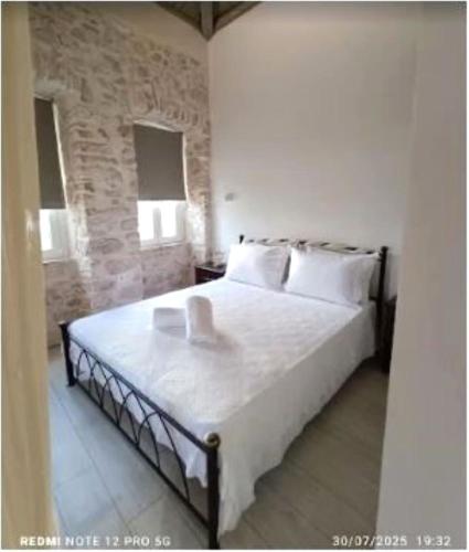 a bedroom with a large bed with white sheets and pillows at Suites-Xenonas "Alexandra's Coffee House" in Volímai