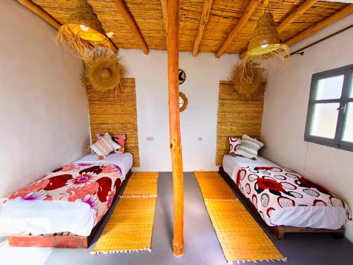 two beds in a room with two windows at SURF TRIP ROOM IN OUASSANe in Essaouira