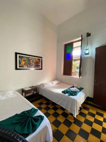 a bedroom with two beds and a checkered floor at Hotel Casa Antigua Buga in Buga