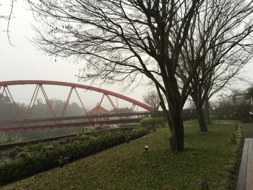 a red bridge over a river with a tree at Rainbow Bridge B&B in Sanzhi