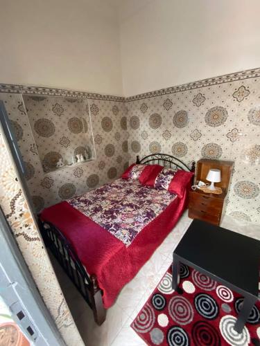 a bedroom with a bed with a red blanket and a table at Cosy Riad Cœur Medina in Rabat