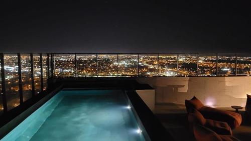 a swimming pool with a view of a city at night at Condomínio Residencial - Hype 017 | by Housi in Sao Jose do Rio Preto