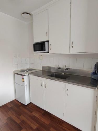 a white kitchen with a sink and a microwave at Gardena Court Motel in Hamilton