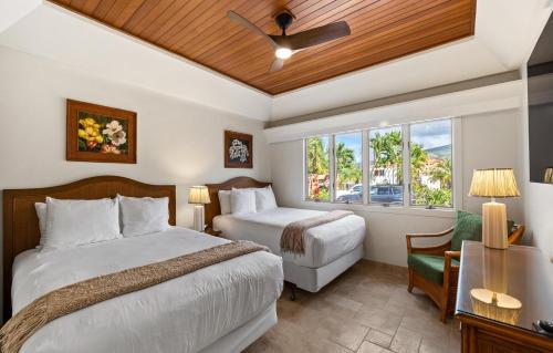 a bedroom with two beds and a window at Puunoa Beach Estate in Lahaina