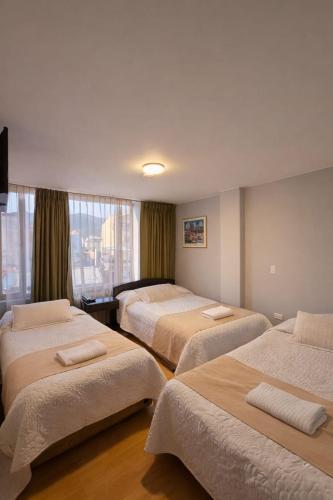 ein Hotelzimmer mit drei Betten und einem Fenster in der Unterkunft Hotel Oicatá in Duitama