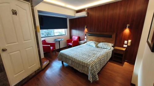 a bedroom with a bed and chairs in a room at HOTEL Y MOTEL SAVOY - Santiago in Santiago