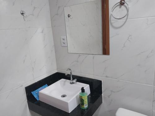 a white bathroom with a sink and a mirror at Chalé Vila do Vento in Lavras Novas