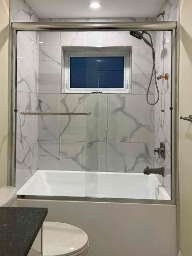 a bathroom with a shower with a tub and a toilet at SixPine - One bedroom suite in Vancouver