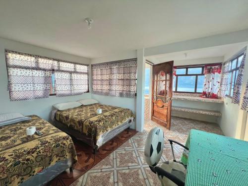 ein Schlafzimmer mit zwei Betten, einem Tisch und Fenstern in der Unterkunft Hotel Henderson in San Pedro La Laguna