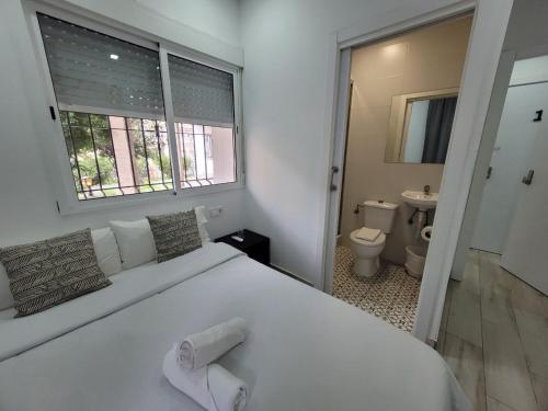 a white bedroom with a large white bed and a bathroom at AYZ Silvela - Auto check-in property in Málaga