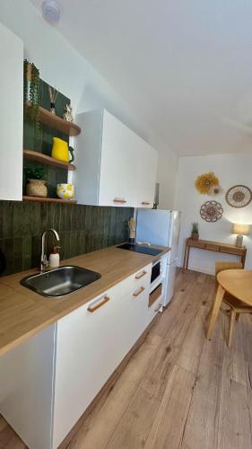 een keuken met witte kastjes, een spoelbak en een tafel bij Casa Sole in Saint-Chamond