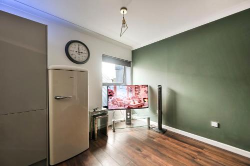 a living room with a tv and a clock on the wall at Bright & Modern Apartment in Hackney Wick E3 in London