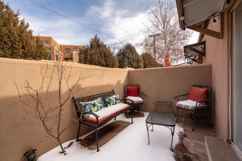 three chairs and a bench on a balcony in the snow at Casita De Alces in Santa Fe