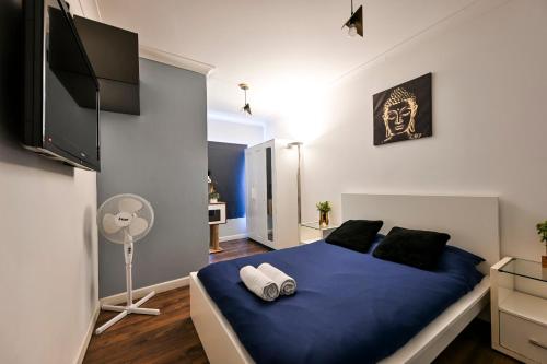 a bedroom with a blue bed and a fan at Bright & Modern Apartment in Hackney Wick E3 in London