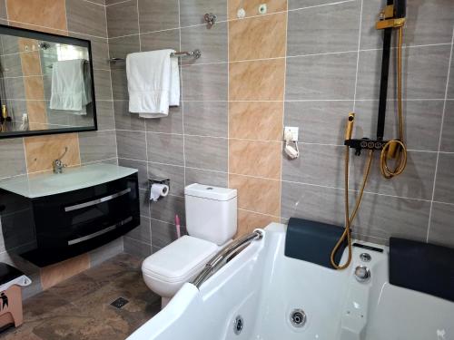 a bathroom with a tub and a toilet and a sink at Pelican VVIP Villa in Wa